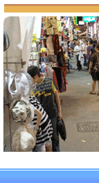 Bustling Ladies Market street with shoppers examining clothing and accessories in a crowded Hong Kong night market