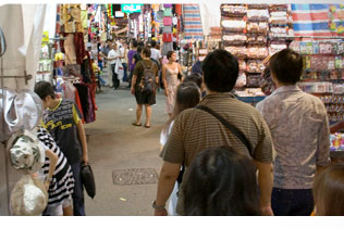 Bustling covered market in Ladies Market, Hong Kong, with shoppers amid stalls of clothing and accessories
