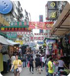 Bustling street market at Ladies Market in Mong Kok, with crowded stalls selling clothes and accessories amid neon signs and shoppers